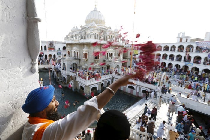 A Sikh devotee throws petals as the procession passes by during the Vaisakhi festival at Panja Sahib shrine in Hassan Abdel(Caren Firouz-Reuters) (98K)